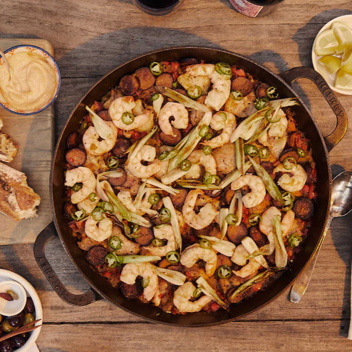 Smithey No. 14 dual handle skillet filled with chicken, shrimp and chorizo paella.