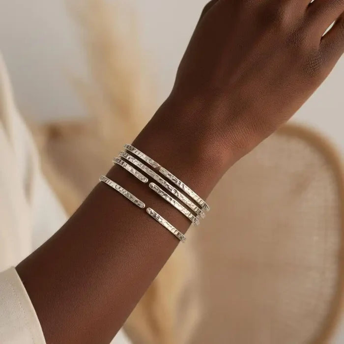 Hand wearing multiple 10 Gauge 925 Silver Hammer Textured Bangles showcasing their unique texture and style.