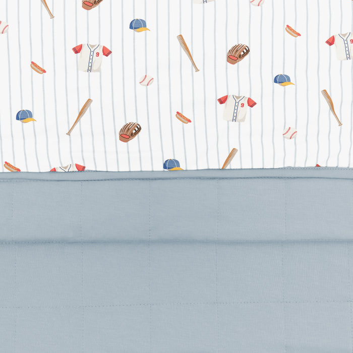 Close up of the Baby Blanket in Home Run showing the muted blue quilted backing and baseball print smooth top layer