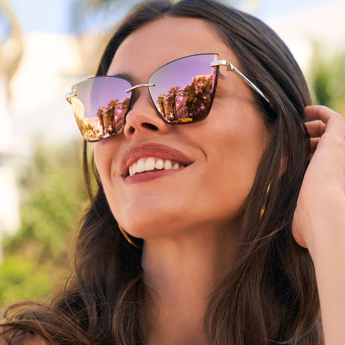 on model - female wearing diff eyewear featuring the becky v cat eye sunglasses with a gold frame and peach mirror lenses angled view