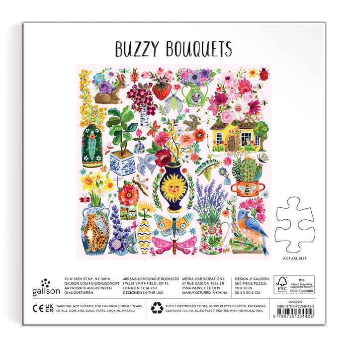 The Buzzy Bouquets 500 Piece Puzzle by Jennifer O Lewis/August Wren comes in a colorful box with painted flowers, birds, butterflies, a beehive, teapot, and cottage gardens. The back displays a puzzle piece for scale and product details.