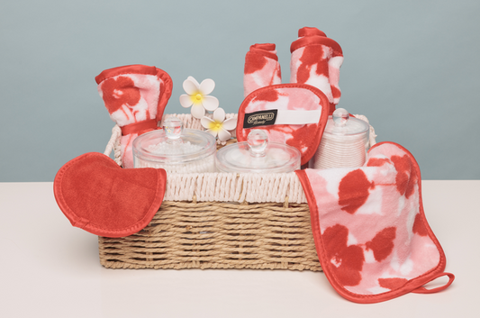 Wicker basket with red and white patterned potholders, oven mitts, and glass containers on a light gray background.