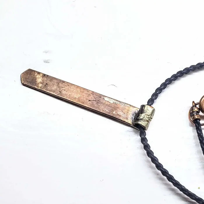 Copper Weave Embossed Necktie Necklace with a bold copper pendant and braided black cord.