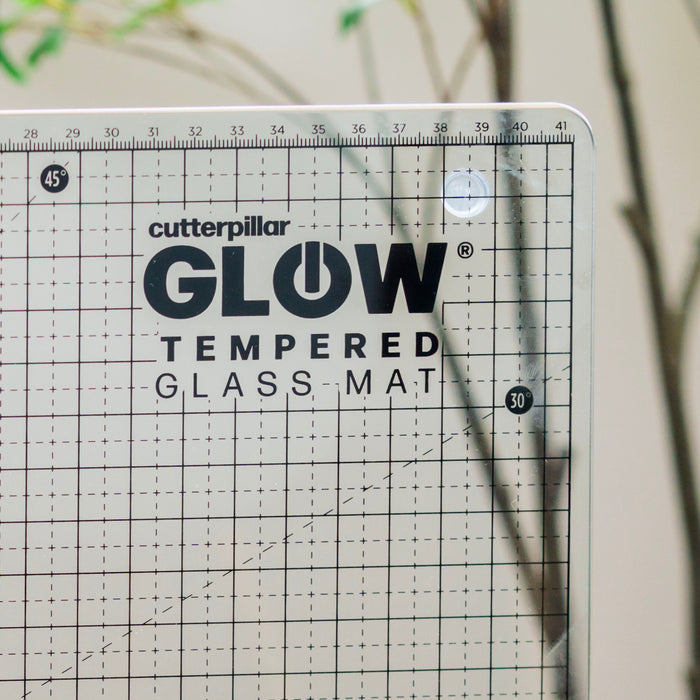 Cutterpillar Glow tempered glass mat with grid pattern on a neutral background