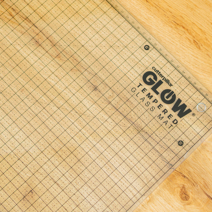 Grid-patterned cutting mat with 'Cutterpillar' branding on a wooden surface