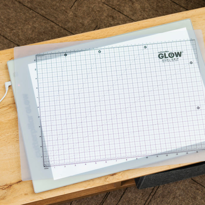 Grid cutting mat with 'Glow' branding on a wooden surface