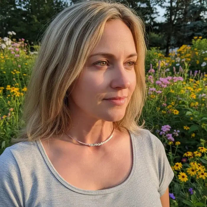 A woman wearing an Ergonomic Copper Sculpted Embossed Wire Gemstone Choker in a vibrant flower garden.