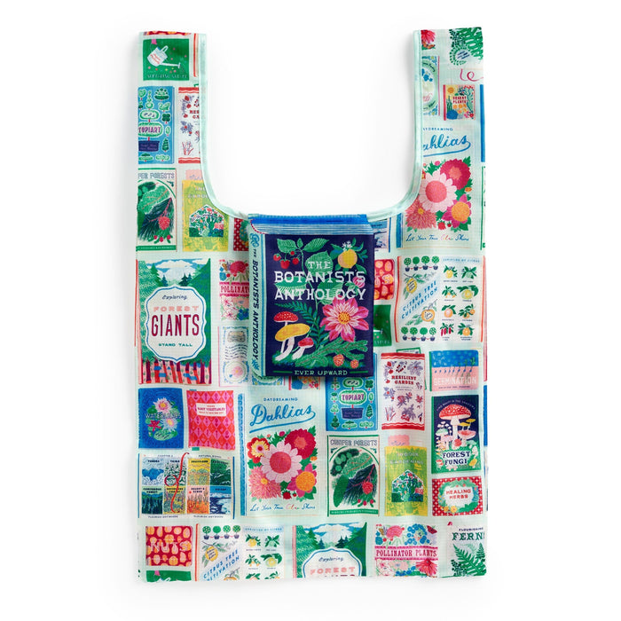 The Emily Taylor Ever Upward Botanist Bookshelf Packable Nylon Tote Bag features colorful vintage-style seed packet, flower, and plant illustrations with a central “The Botanist’s Anthology” design.
