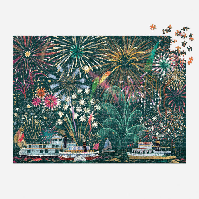The Sarah Long Fireworks Jubilee 1000 Piece Foil Puzzle features vibrant fireworks over boats on a river at night, with a few pieces missing in the upper right corner.