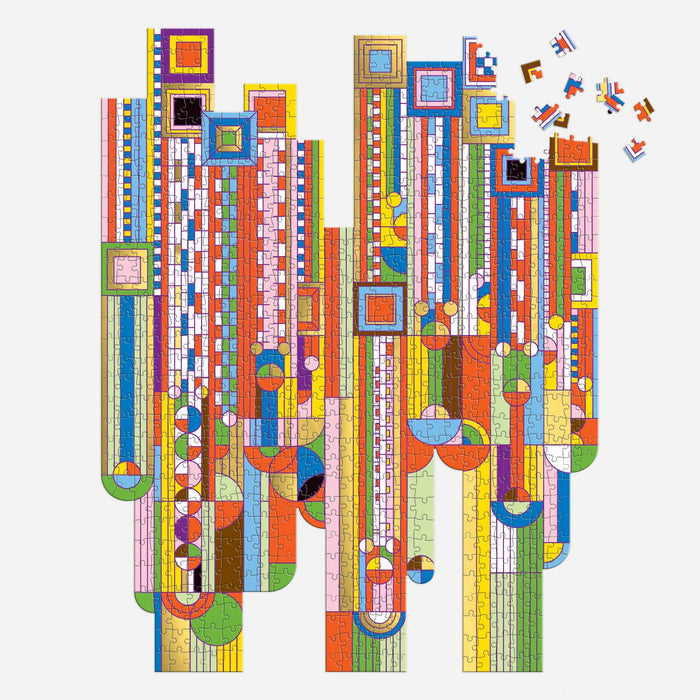The Frank Lloyd Wright Foundation's Saguaro Forms & Cactus Flowers 750 Piece Shaped Foil Puzzle features vibrant, geometric patterns inspired by Wright’s iconic design, with scattered pieces displaying colorful stripes, circles, and squares.