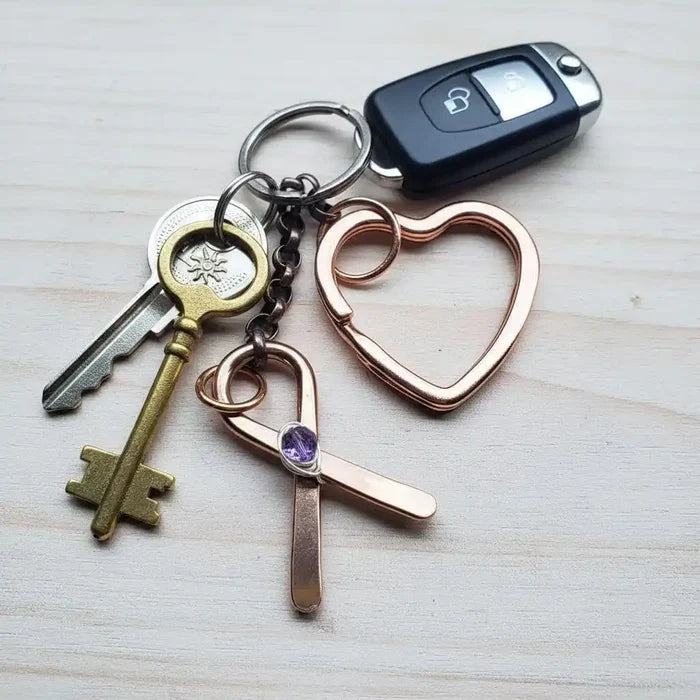 Handmade Caregiver Crystal Copper Ribbon Heart Key Chain with keys and a car remote on a wooden surface.