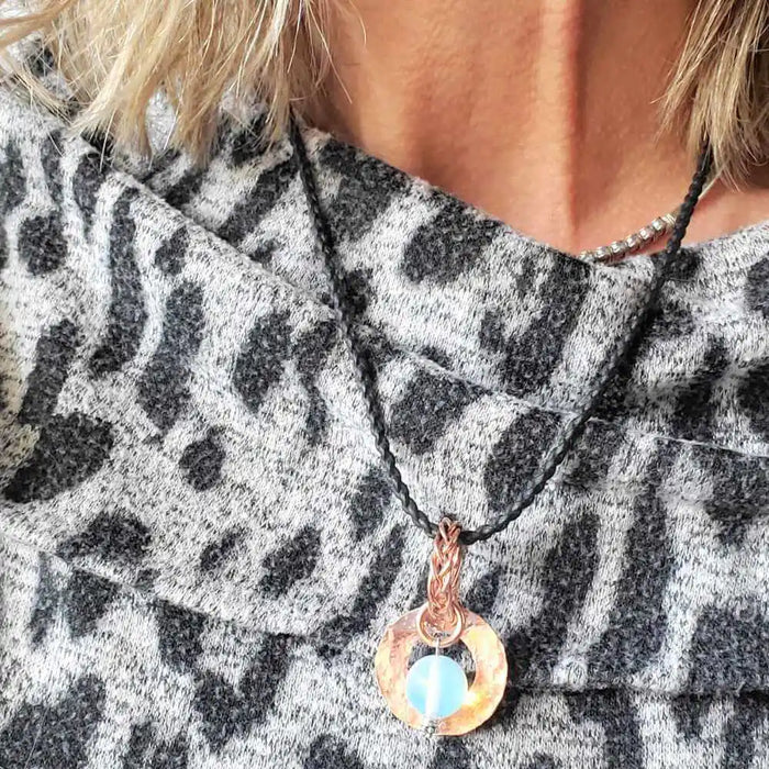 Handmade copper wire braided bail gemstone necklace featuring a rare Luminite gemstone on a model's neck.
