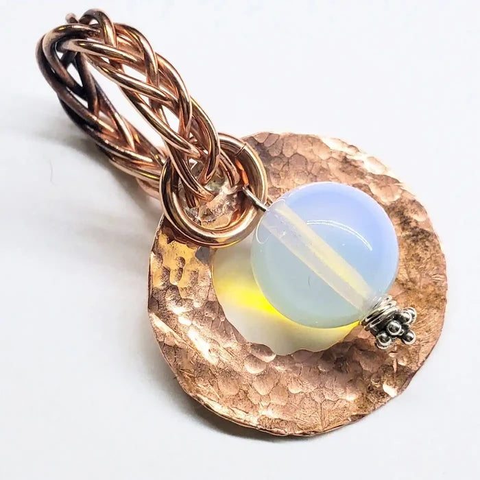 Handmade copper wire braided bail gemstone necklace featuring a rare Luminite gemstone on a copper backdrop.