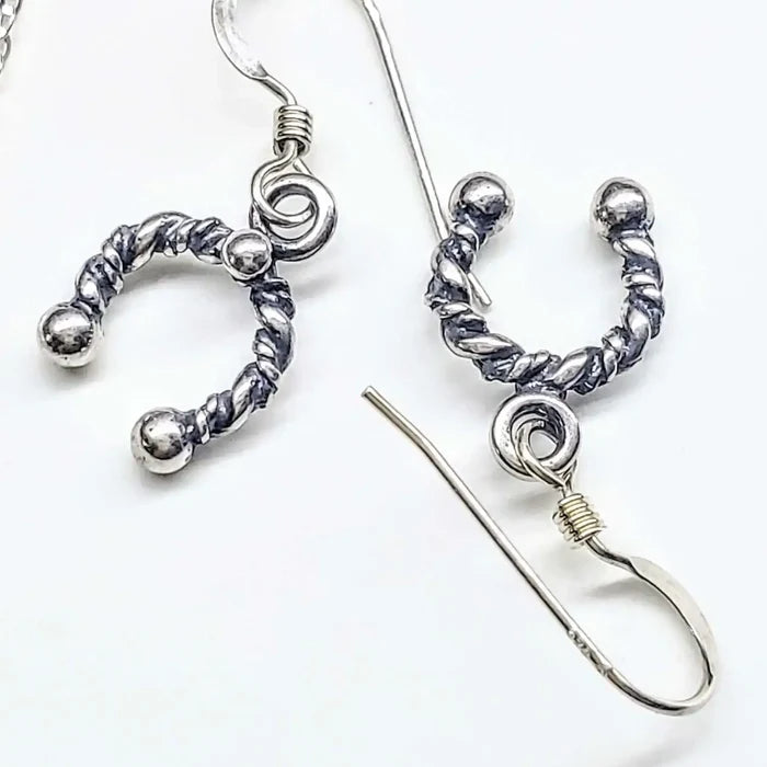 Handmade sterling silver horseshoe jewelry earrings featuring a twisted design and elegant details.