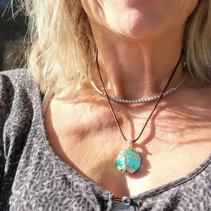 Handmade tree of life dichroic pendant necklace worn by a woman, showcasing its vibrant colors and unique design.