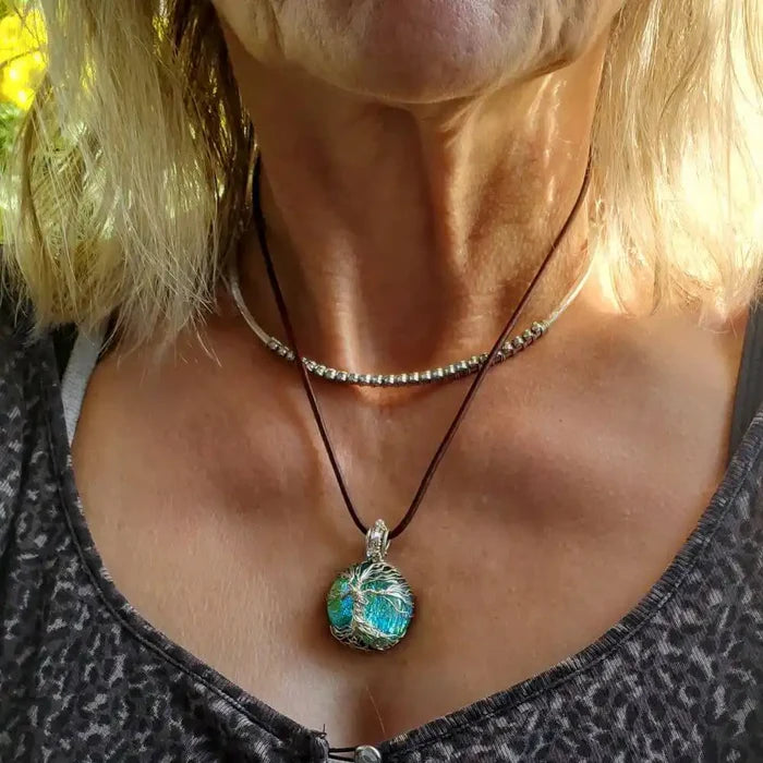 Handmade tree of life dichroic pendant necklace showcased on a woman, featuring vibrant colors and intricate design.