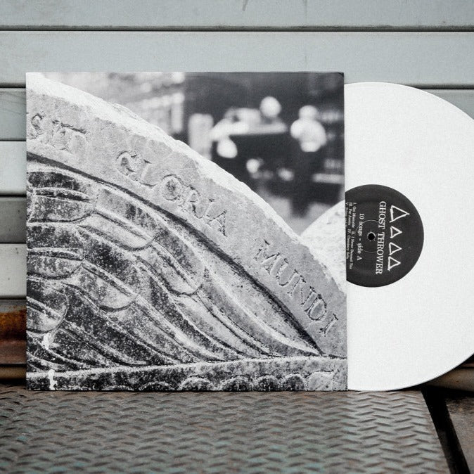 A white Limited Pressing LP by Ghost Thrower, partially in its sleeve featuring a black-and-white image of an old stone engraved with "GLORIA MUNDI," set against a grey metal background with horizontal lines.