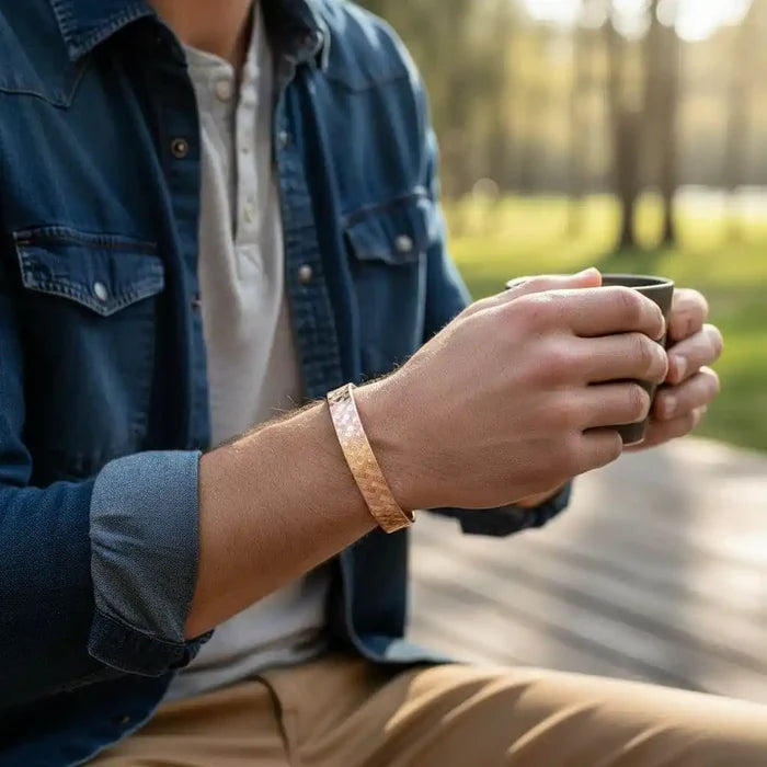 His and Her Copper Embossed Weave Cuffs 16 Gauge worn by a man holding a cup in a natural outdoor setting.