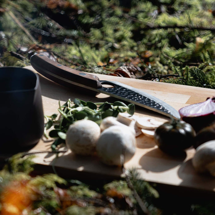 Wooden cutting board with mushrooms and a knife on a natural background