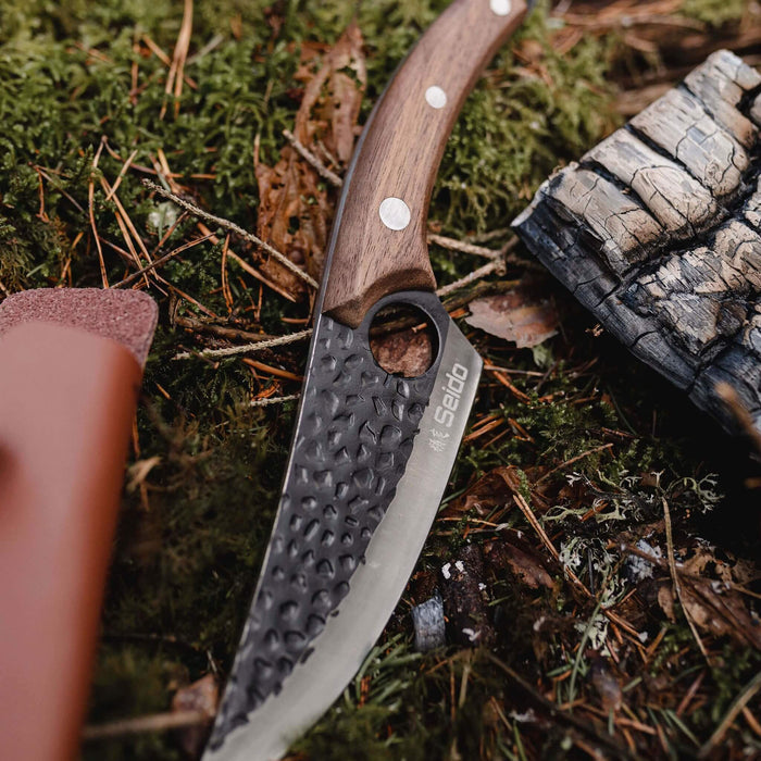 Folding knife with wooden handle on a mossy ground