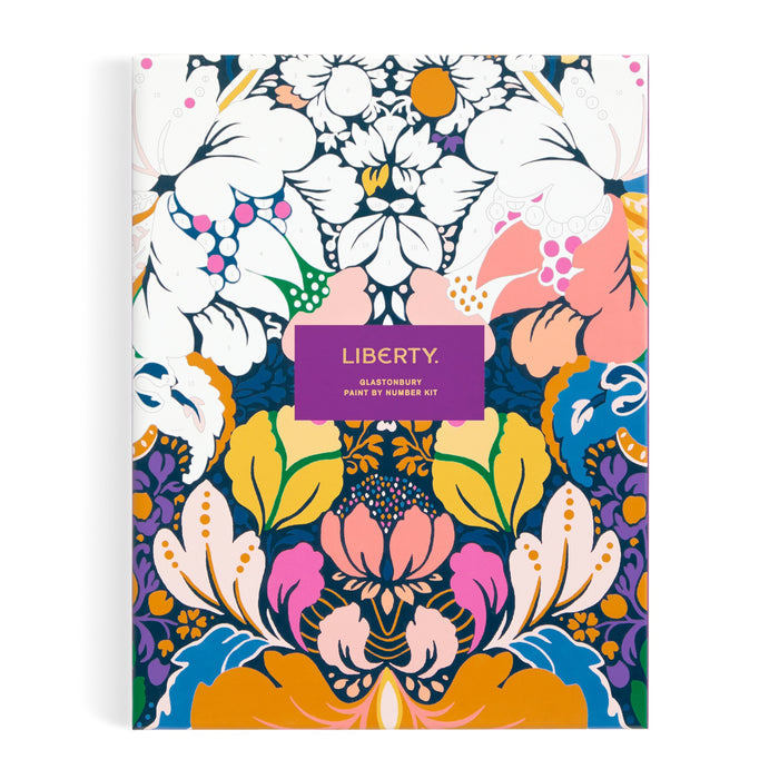 A vibrant, symmetrical floral pattern in blues, pinks, oranges, purples, and white centers on a purple LIBERTY label. Inspired by Glastonbury, this is the Liberty London 9 x 12 Paint by Number Kit with premium acrylic paints.