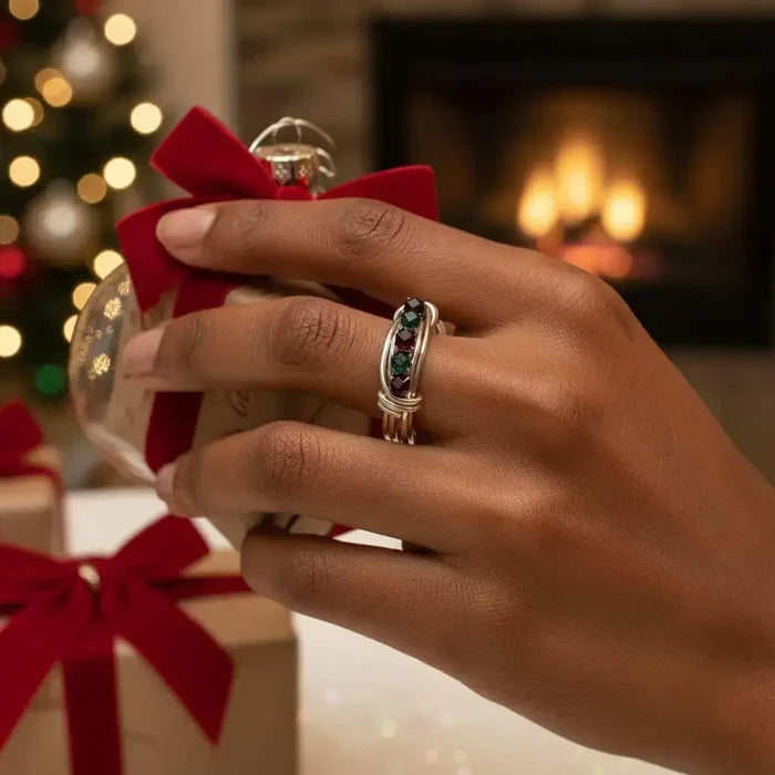 Limited edition 2026 silver wire wrapped Christmas ring worn by a hand holding a gift, with a festive background.