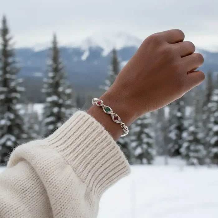 Limited Edition Red Green Christmas Holiday Tube Bracelet worn on a hand, set against a snowy mountain backdrop.