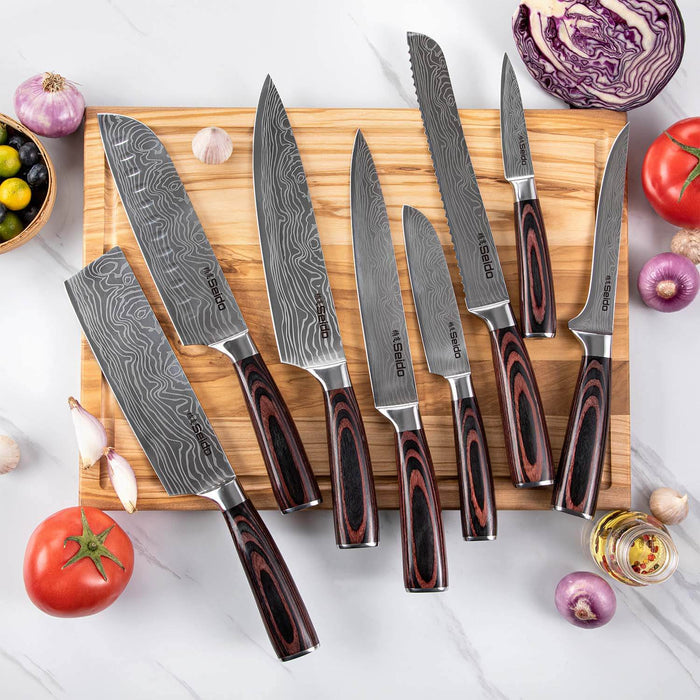Set of knives with wooden handles on a cutting board surrounded by vegetables.