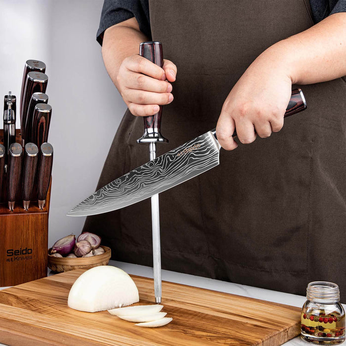 Person holding a large knife over a cutting board with onions, surrounded by other knives and kitchen items.