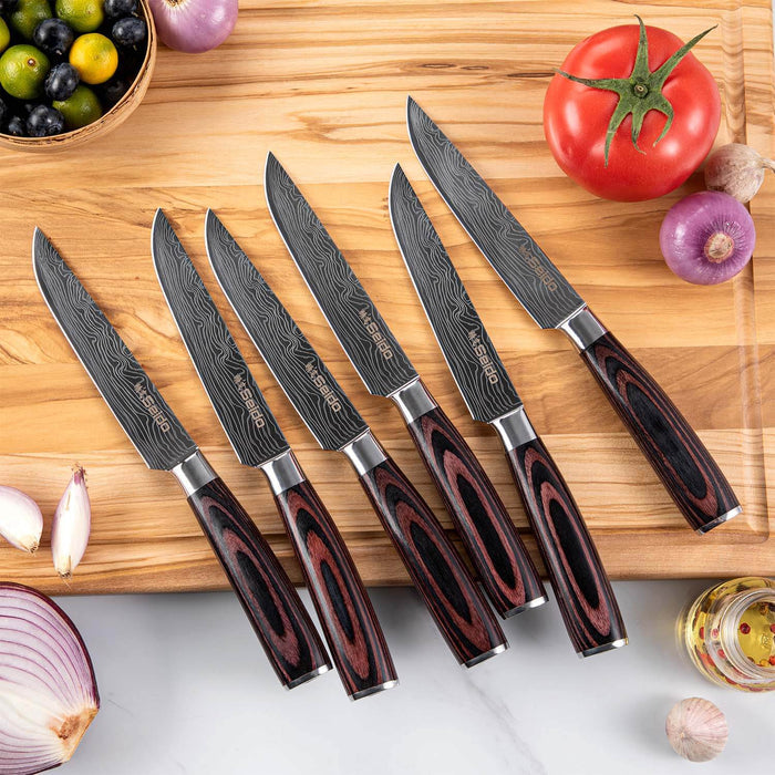Set of six Damascus steel kitchen knives with wooden handles on a wooden cutting board with vegetables.