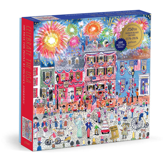 The Michael Storrings Celebrate The USA 500 Piece Foil Puzzle features a festive parade with flags, decorated houses, and fireworks, honoring America’s 250th anniversary (1776–2026).