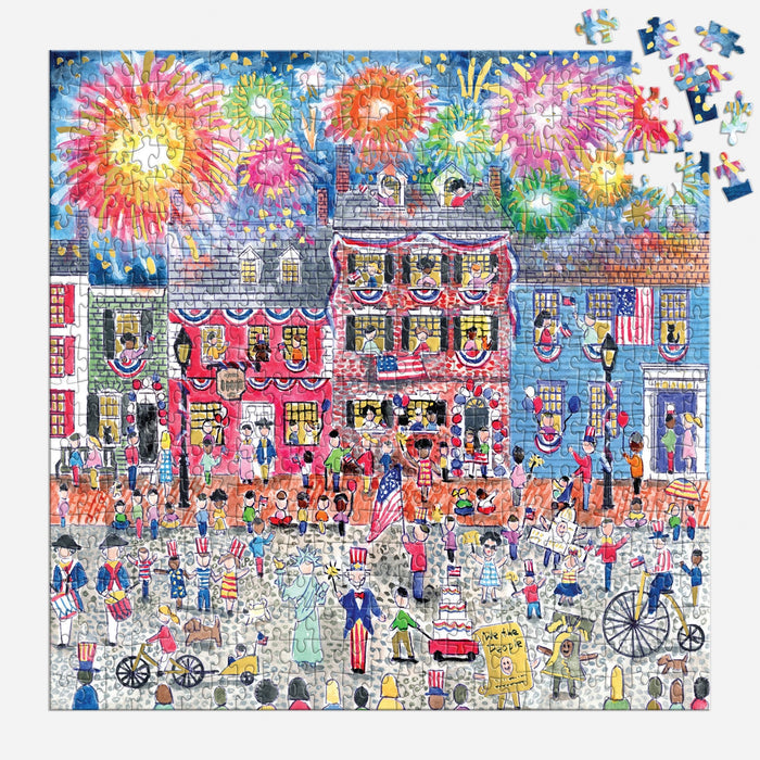 The Michael Storrings Celebrate The USA 500 Piece Foil Puzzle by Michael Storrings features a vibrant Fourth of July street parade with people in patriotic attire, American flags, fireworks, and a few missing pieces in the top right corner.