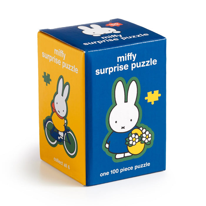 The Miffy 100 Piece Surprise Puzzle by Miffy comes in a blue and yellow box with Miffy illustrations, including holding flowers and riding a bike. Each box has one 100-piece puzzle; collect all six surprise designs!.