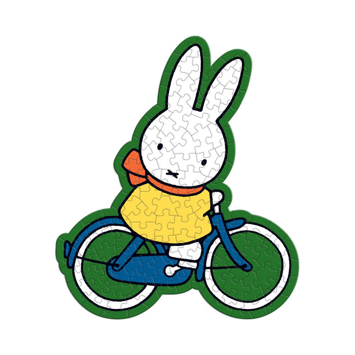 The Miffy 100 Piece Surprise Puzzle by Miffy features an illustrated white bunny in a yellow shirt and red scarf, riding a blue bicycle. The completed puzzle displays visible piece lines for a classic jigsaw look.