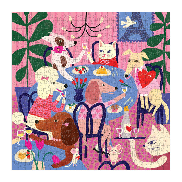 The Anne Bentley Paws for Love 500 Piece Puzzle features six dogs gathered around a dining table in a vibrant, plant-filled room with pink walls—an ideal, cheerful gift for dog lovers.