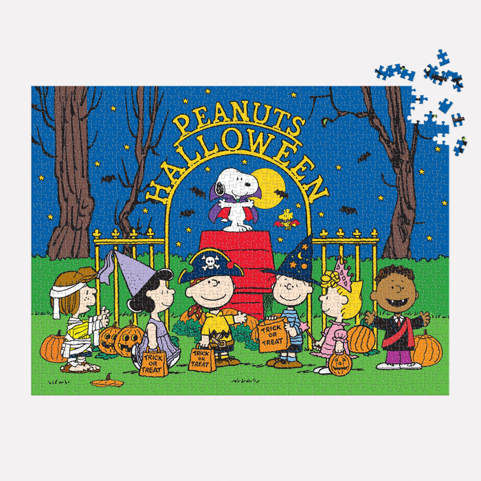 The Peanuts Halloween 1000 Piece Puzzle by Peanuts Worldwide, LLC shows Charlie Brown and friends in costumes trick-or-treating with Snoopy as the Red Baron and “Peanuts Halloween” above. A few pieces are missing from the top right corner.