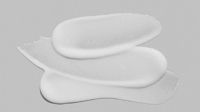 Three white, oval-shaped adhesive pads stacked on top of each other on a solid gray background.