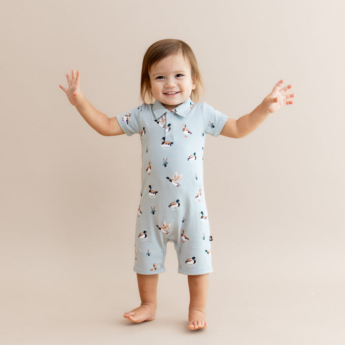 Young toddler standing with his arms out at the side wearing the Polo Shortall in Mallard Duck