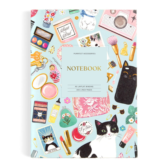 The Purrfect Accessories Premium A5 Notebook by Christine De Carvalho features a light blue cover with cat, makeup, and accessory illustrations, NOTEBOOK label, and lined pages—a stylish choice for cat stationery lovers.