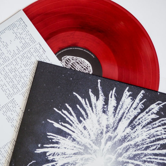 A limited edition translucent red & black marble vinyl by Gatherers, partially covered by its black-and-white Quiet World album cover with an abstract white burst design, and includes an insert with printed text.