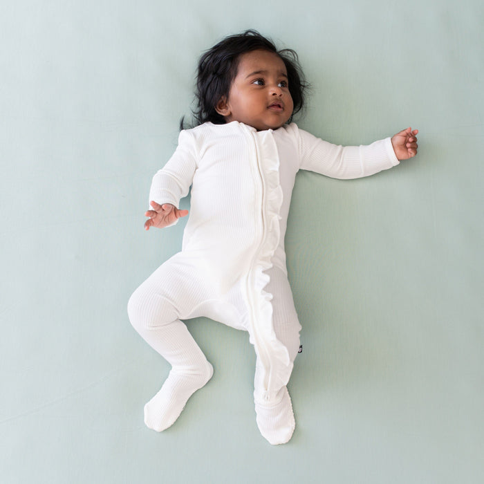 Infant wearing Kyte Baby Ribbed Ruffle Zipper Footie in Cloud
