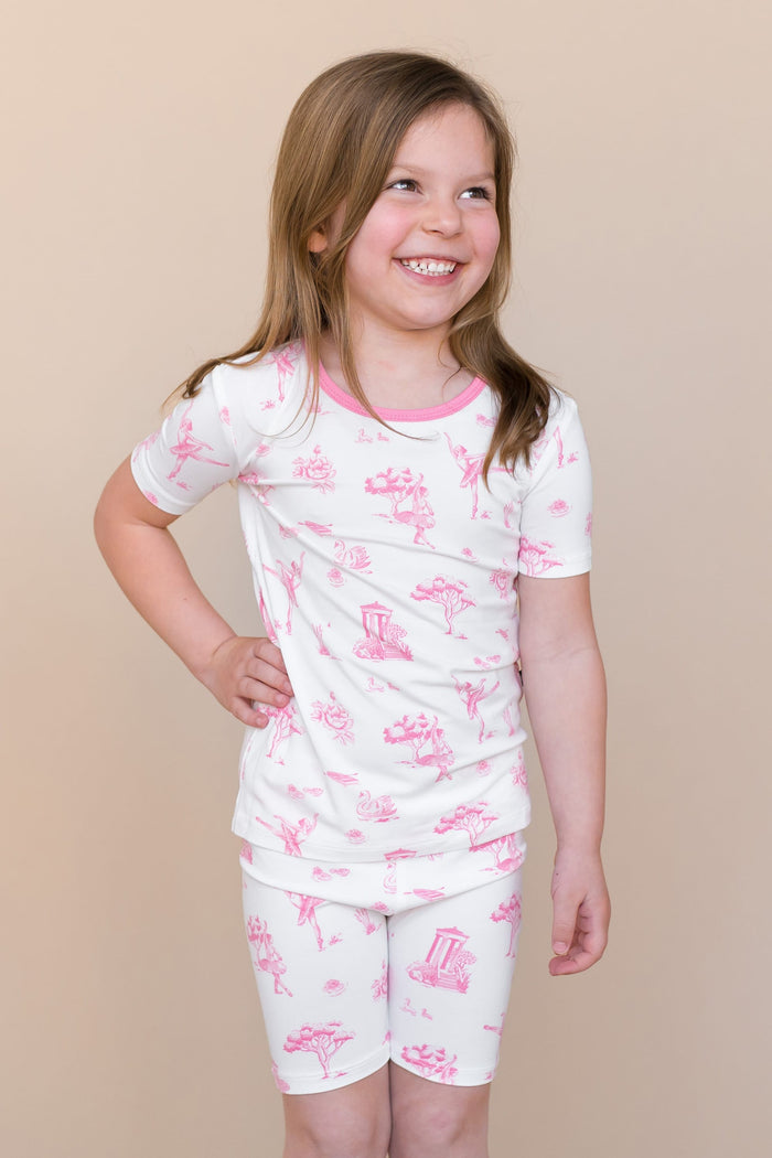 Young smiling girl posing with one hand on her hip wearing the Short Sleeve Pajamas in Toile Ballet
