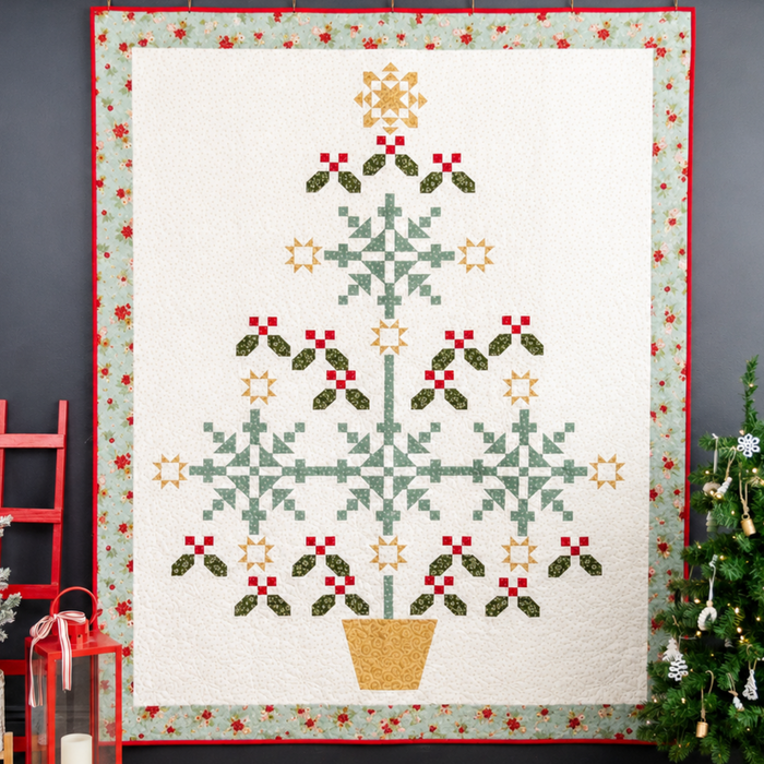 Christmas-themed quilt with tree design on a dark wall with decorative elements.