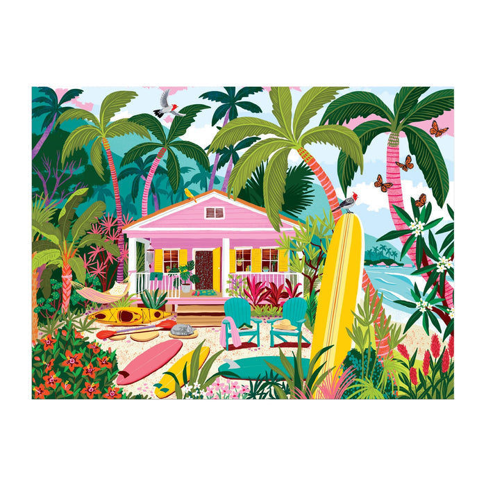 The Surfside Bungalow 1000 Piece Puzzle by Julia Cornelius features a vibrant tropical scene with a pink beach house, palm trees, colorful flowers, surfboards, kayaks, Adirondack chairs, a hammock, ocean views, birds, and butterflies.