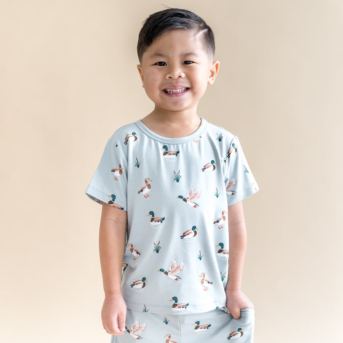 Smiling boy wearing the Toddler Basic Tee in Mallard Duck paired with matching drawstring shorts