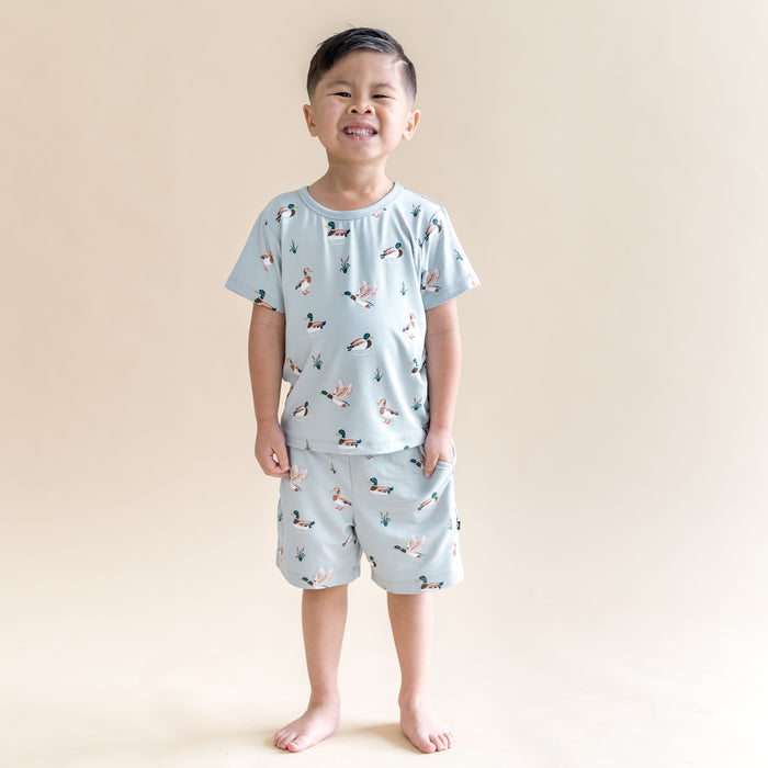 Smiling boy wearing the Toddler Basic Tee in Mallard Duck paired with matching drawstring shorts