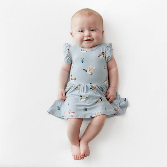 Smiling infant wearing the Twirl Bodysuit Dress in Mallard Duck