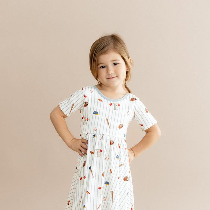 Close up of young girl wearing the Twirl Dress in Home Run with her hands on her hips
