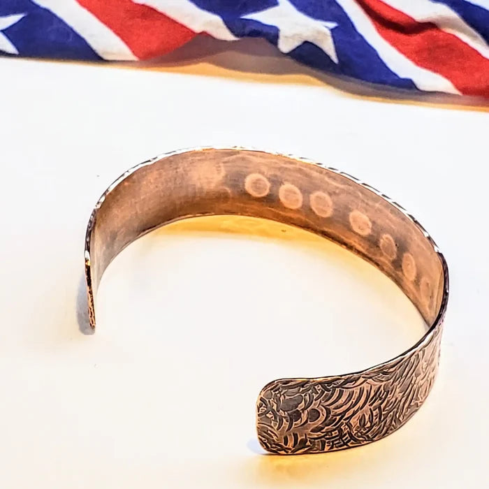 Copper bracelet with intricate patterns on a white background
