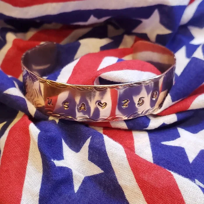 copper bracelet with engraved text USA 250 on an American flag background